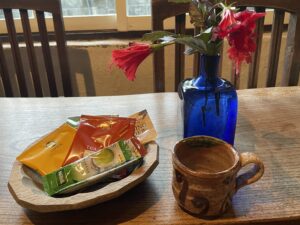 リビングの木のテーブルに、コーヒーカップとハイビスカス。木の皿の中には、自宅から持ってきた紅茶のティーバッグ類