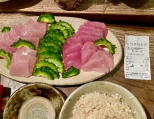 比川共同売店で買った2種類のサシミ。彩りとしてゴーヤーのスライスを添えて皿に盛った。レシートも添付。